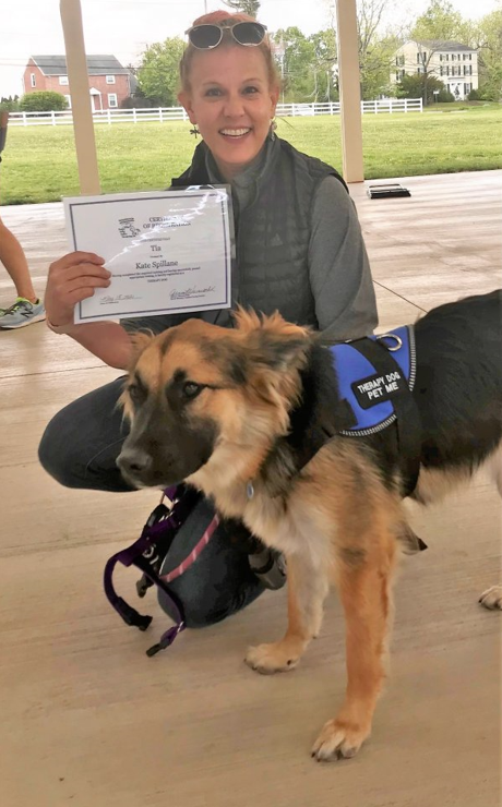 Kate Spillane holding a therapy dog certification next to her German Shepherd Tia